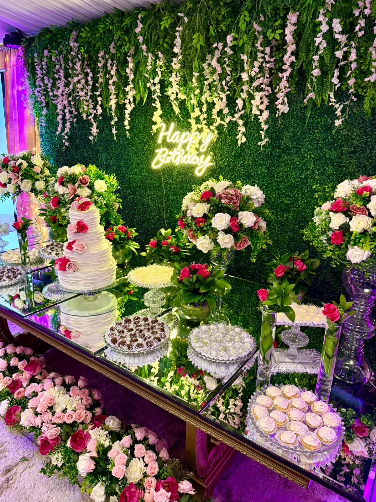 Mesa do bolo e doces com arranjos florais