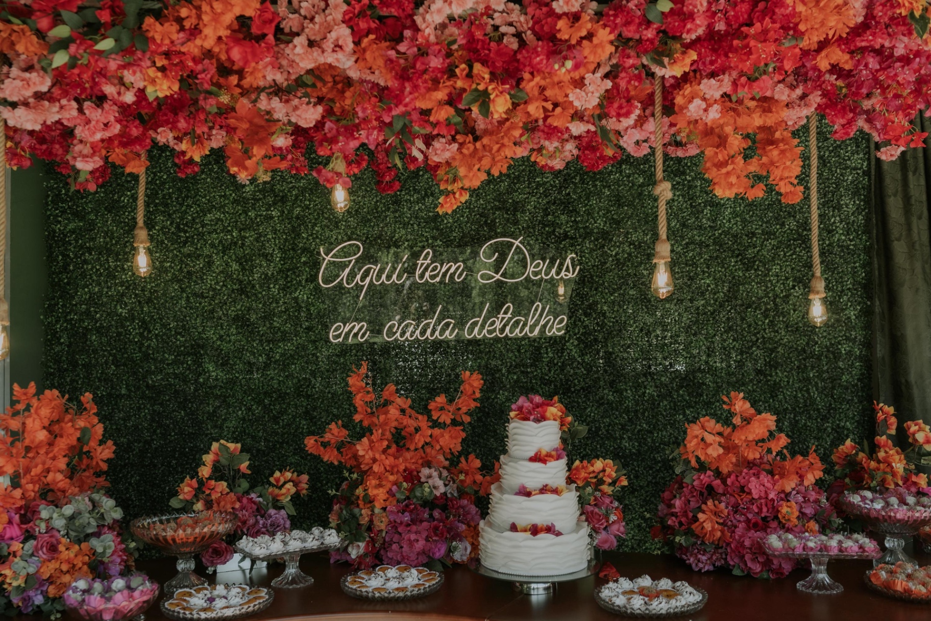 Mesa do bolo com parede de folhagem e flores