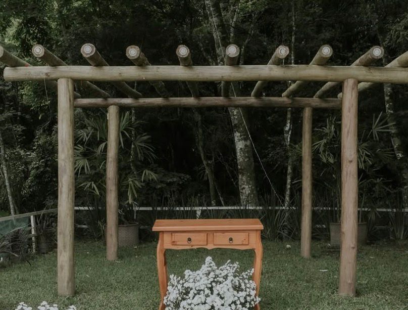 Pergolado de madeira com aparador e arranjo de flores brancas