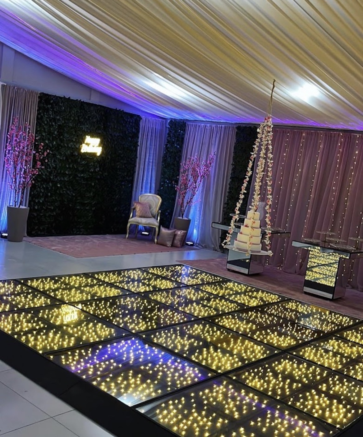 Salão decorado com pista iluminada e mesa de bolo